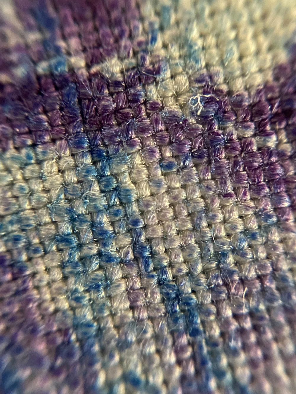 Foto referencial: Hilos azules y violetas en una trama tejida
